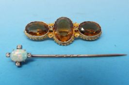 A yellow metal brooch marked 12ct set with three oval cut citrines and a stick pin set with an oval