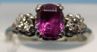 An 18ct gold ring set with a step cut oval ruby flanked by two diamonds in platinum setting (size