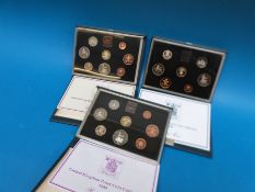 Three UK proof coin collections by the British Royal Mint in deluxe cases, comprising 1983,