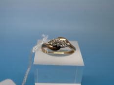 A 9ct gold ring set with a round brilliant cut diamond flanked by three smaller diamonds to each
