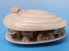 A carved Chinese ivory netsuke in the shape of an open shell with carved detail within