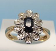 An 18ct gold ring set with an oval cut sapphire surrounded by diamonds in a platinum setting (size