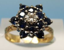 An 18ct gold ring set with sapphires and a central diamond in a flower cluster (size M)