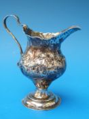 A Georgian hallmarked silver cream jug with embossed decoration, London 1780,