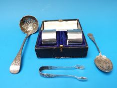 A cased pair of hallmarked silver napkin rings, silver sifter spoon,