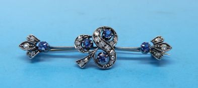A yellow metal brooch set with diamonds and sapphires in the shape of a clover/shamrock