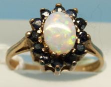 A 9ct gold ring set with an opal surrounded by sapphires (size L)