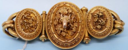 A Victorian gold bracelet formed of heavy links joining three oval filigree panels with a ram to