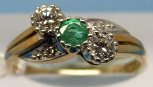 An 18ct gold ring set with an emerald flanked by diamonds in a twist setting (size N)