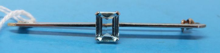 A yellow metal bar brooch set with an emerald cut aquamarine