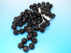 A Chinese single row necklace of 70 spherical carved and pierced cherry amber style beads,