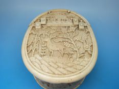 An oval ivory casket with hinged lid carved with deer in a wooded landscape,