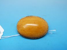 An amber pebble brooch set in an embossed 9ct gold mount in the form of stylized leaves, 5cm x 3.