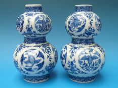 A pair of 19thC Chinese double gourd vases with blue and white stylized flower and phoenix