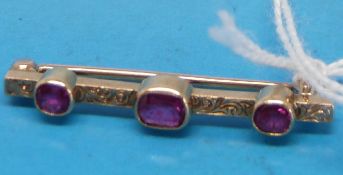 An Edwardian yellow metal brooch set with three synthetic rubies