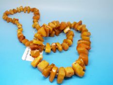 An amber necklace formed of 82 egg yolk coloured irregularly shaped beads, the largest measuring 1.