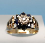 A 9ct gold ring set with a diamond surrounded by sapphires (size J)