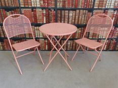 A pink and metal garden table and two folding chairs