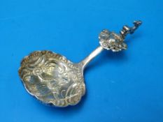 A late 19thC continental white metal figural caddy spoon with repoussé decoration to the bowl,