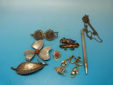 A silver brooch in the shape of a clover/shamrock set with a coral to the centre,