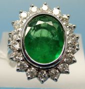 A white metal ring marked 750 set with an oval cut emerald measuring approximately 3.