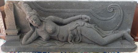 An Indonesian carved volcanic stone sculpture of a reclining topless Buddha on a plinth,