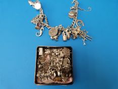 A silver charm bracelet with various charms on with a further collection of charms (over 30)