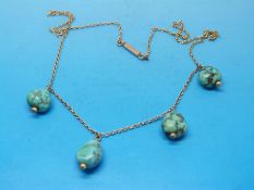 A yellow metal necklace set with four turquoise stones
