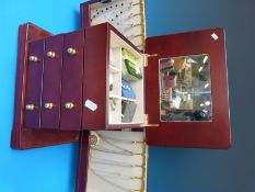 A modern jewellery box with three drawers and side opening compartments with silver necklaces,