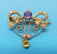 An Edwardian brooch marked 15ct set with an amethyst and seed pearls with a peridot dropper