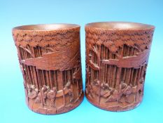 A pair of Chinese bamboo brush pots carved with scenes of scholars reading and playing chess,