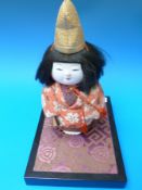 A Japanese doll on plinth possibly a present from Prince Chichibu