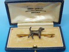 A yellow metal bar brooch set with a foxhound marked 9ct (in original box, Hardy Bros,
