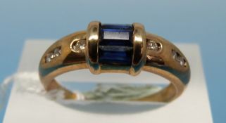 A yellow metal ring set with three baguette cut sapphires and three diamonds to each shoulder (size