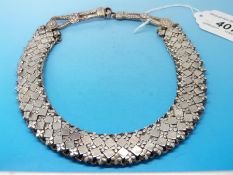 A white metal Indian or Eastern necklace with diamond and flower design,