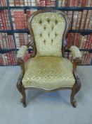 A carved Victorian walnut elbow chair with scrolling detail raised on castors