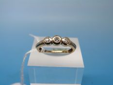 A 9ct gold ring set with three diamonds in a rubover setting with textured shoulders (size P)