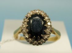 An 18ct ring set with a central sapphire surrounded by diamonds (size K)