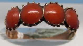 A yellow metal ring set with four coral cabochons (size J)