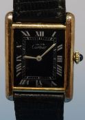A ladies' Cartier wristwatch with Roman numerals on a rectangular black face