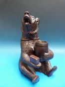 A musical Black Forest carved tobacco container in the form of a bear holding a barrel,