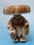 A Japanese ivory figural netsuke in the form of a man carrying a lantern