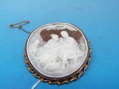 A cameo brooch depicting a couple in a garden with 9ct gold surround