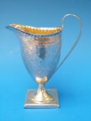 A Georgian hallmarked silver helmet shaped jug with engraved decoration and gilt interior,