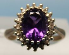 A 9ct gold ring set with a large amethyst surrounded by diamonds (size O)