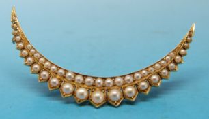 A yellow metal brooch set with pearls in a crescent shape