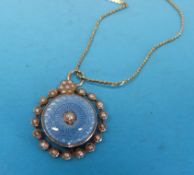 A Victorian gold pendant set with guilloché blue enamel surrounded by seed pearls on a yellow metal