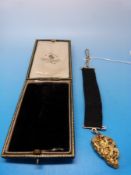 A large natural gold nugget on ribbon and yellow metal suspension bar (nugget approximately 14g)