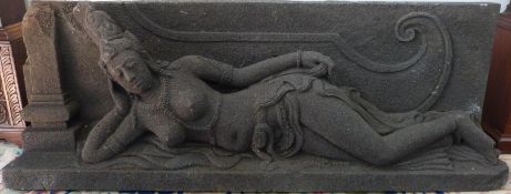 An Indonesian carved volcanic stone sculpture of a reclining topless Buddha on a plinth,
