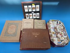 A tin of approximately 50 sets of cigarette cards and a box of empty albums